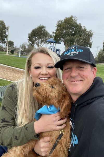 A man and woman holding a dog in their arms.